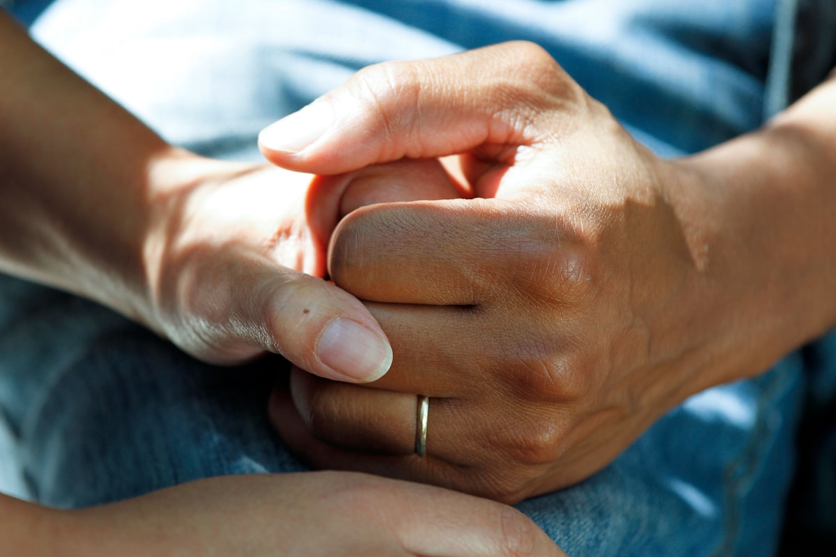 Two people holding hands, one offering comfort to the other